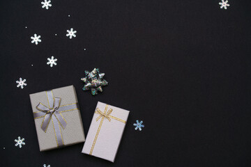 Christmas background from gift boxes of silver color, decorative snowflakes on dark black background. Festive christmas background. Banner layout, postcard. Flat lay. Copy space.