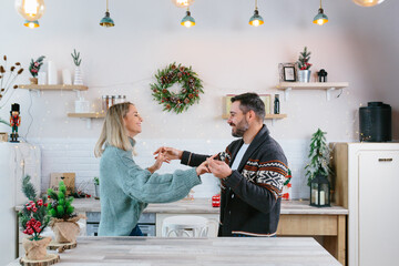 Young couple husband and wife happy preparing for New Year and Christmas celebration, family having fun dancing in the kitchen