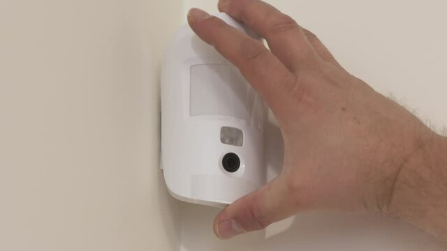 Indoor security system equipment, installation of smart motion sensor, wireless alarm motion detector mounting on the wall of the house. High quality 4k footage