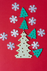 Fototapeta na wymiar flat wooden christmas tree shapes arranged on a red paper background