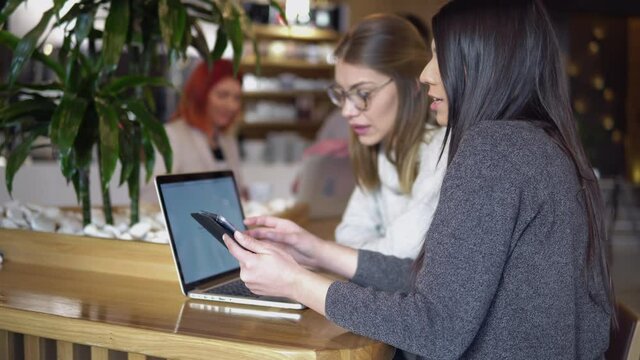 Two young business developer women sitting during a coffee time with a laptop and discussing and planning the business plan of a start up company