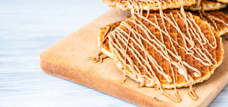 Traditional local authentic Dutch Netherlands sweet fresh homemade tasty stack brown golden waffle melt salted caramel honey syrup for dessert in cafe with hot warm coffee milk tea call Stroopwafel
