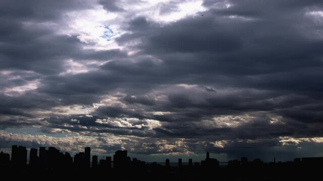 City Skyline with heavy storm clouds rolling through in time lapse sequence