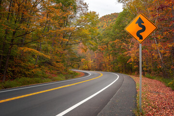 winding road signpost with fall foliage on highway © lonewolf565