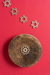 grungy circular wooden object with laser cut flower shapes on red paper
