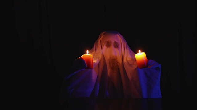 halloween carnival celebration show party: home ghost sheet costume, burning candle scary horror performance concept. scary terrifying holiday spectacle for children 