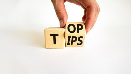 Top tips symbol. Businessman turns a wooden cube with words 'Top tips'. Beautiful white table,...