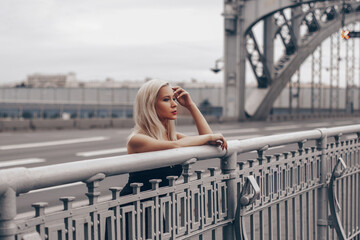 Young luxury blonde woman staying on the bridge and dreaming