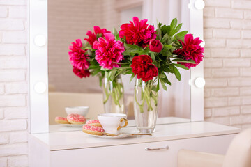 Client place in hairdressing beauty salon with cup of tea, donuts and peonies flowers