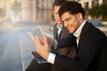 Financiers are working to create new jobs. Confident bankers in business suits. They use gadgets and surf the Internet. Managers meeting near the office, discussing a new project.