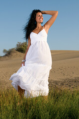 woman on sand enjoying spring or summer sun dressed in white clothes