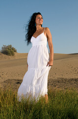 Fototapeta na wymiar woman on sand enjoying spring or summer sun dressed in white clothes