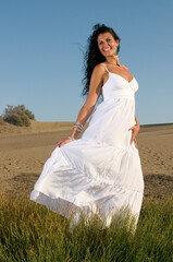 Fototapeta na wymiar woman on sand enjoying spring or summer sun dressed in white clothes