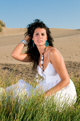 woman on sand enjoying spring or summer sun dressed in white clothes