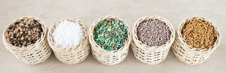 Chemical fertilizers are in wooden baskets with plants placed on a white background. Concept...