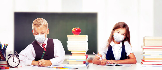 Young children with protection masks against corona virus at school.