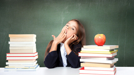 Tired little child girl sleeping on the desk at school.