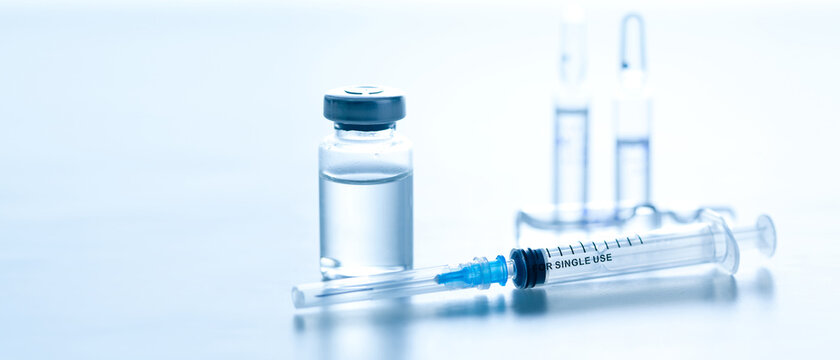 Medical syringe with a needle and a bollte with vaccine.