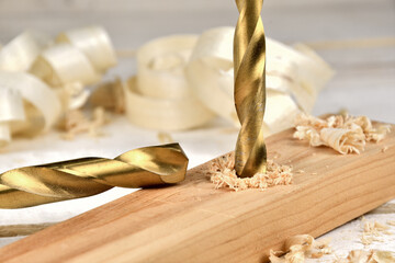 Golden Twist drill bit cutting through wood piece