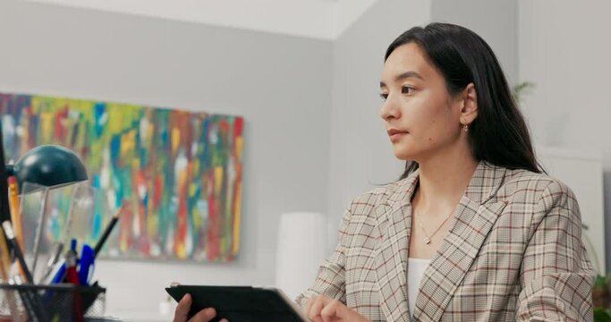 A conscientious organized office worker in a large corporation sits at desk synchronizing documents on tablet with computer, comparing data, clicking the screen, scrolling, focused on her work