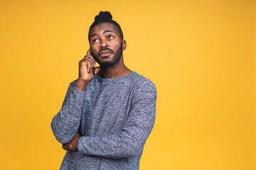 Portrait of a happy african american black man talking on mobile phone isolated over yellow background. Using phone.