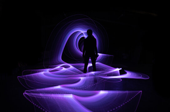 Silhouette Of A Person Standing In Front Of A Neon Purple Wave In A Dark Place