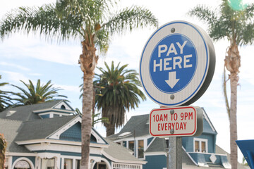 Pay parking sign on a sunny day with palm trees in the background