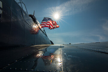 The American Flag flying proud on a warbird with the Sun back lighting it.