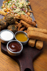 minced with french fries chedar verdeo and cheese with chicken sticks and vegetable croquettes with sauces on wooden board