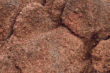 weathered pink granite and red soil eroded by water and forming patterns