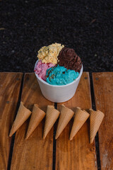 A multi-flavored ice cream with 8 cones on a wooden table.