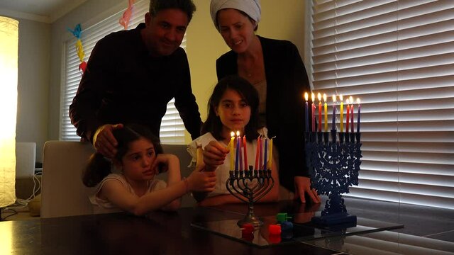 Jewish family kindling candles on candelabrum (hanukkiah) on the eight day of Hanukkah Jewish holiday festival commemorate the rededication of Jerusalem Second Temple in the 2nd century BCE.