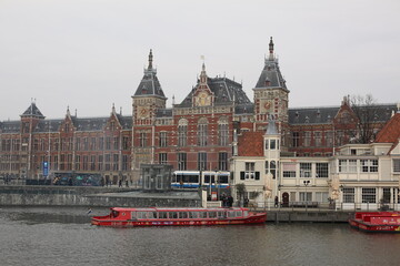 historical architecture of amsterdam station in front of the canal in winter netherlands