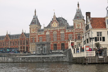 historical architecture of amsterdam station in front of the canal in winter netherlands - obrazy, fototapety, plakaty
