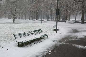 Fototapeta premium long bench in snow-covered park in milano city
