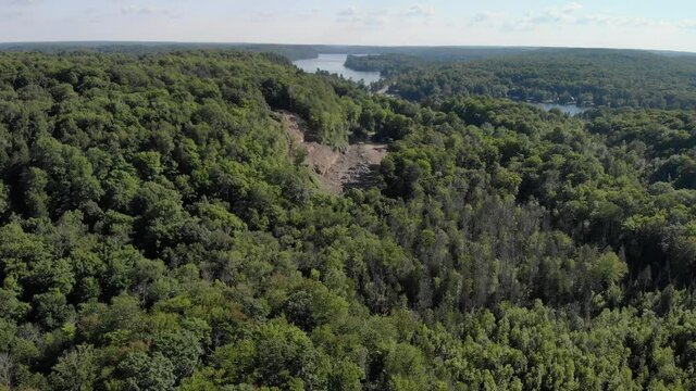 An aerial view of a small open quarry on a forested hilltop.
