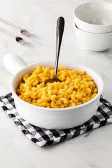 A dish filled with homemade macaroni and cheese with a spoon submerged inside.