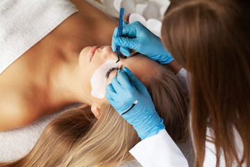 Young woman undergoing procedure of eyelashes lamination in beauty salon