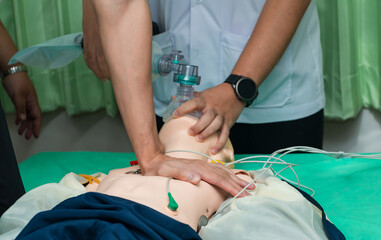 CPR training medical procedure - Demonstrating chest compressions on CPR doll in the class