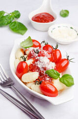 Gnocchi with tomatoes, red sauce, cheese and basil leaves