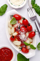 Gnocchi with tomatoes, red sauce, cheese and basil leaves