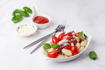 Gnocchi with tomatoes, red sauce, cheese and basil leaves
