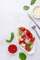 Gnocchi with tomatoes, red sauce, cheese and basil leaves