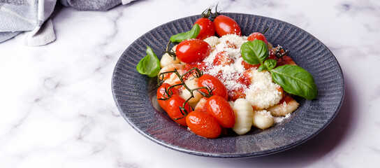 Gnocchi with tomatoes, red sauce, cheese and basil leaves