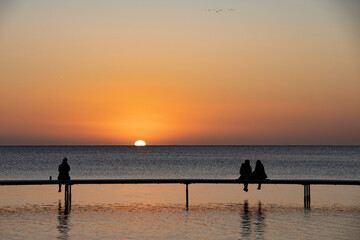 Small group of people sitting on a bridge in Scandinavian enjoying the sunrice