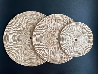 Round shape woven rattan placemat on black background, handmade kitchenware, weave craft product 