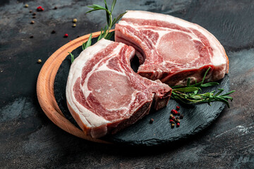 raw pork chop steak with spices and rosemary. pork, beef, chop on a bone. top view. place for text