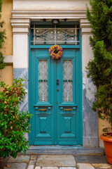 Fototapeta na wymiar Vintage closed door color Bismark blue and a colored flower Wreath hanging on it.