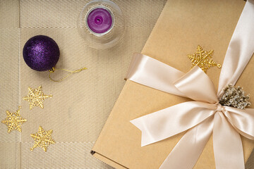 Close up of a Christmas or New Year brown gift box with champagne gold color ribbon. Flat lay Christmas decoration.