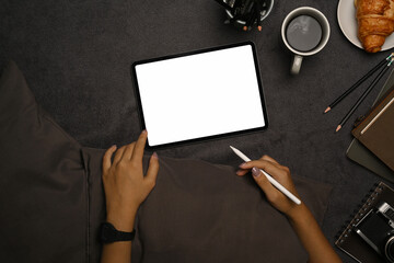 Above view young woman holding stylus pen and using digital tablet on gray carpet.